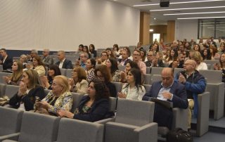 dezenas de pessoas sentadas num auditório a assistir a uma apresentação