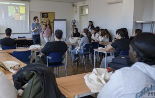 Professores e alunos numa sala de aula a dar testemunho a visitantes