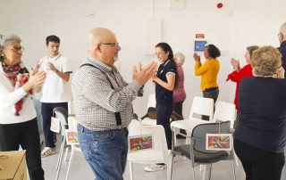 Grupo de idosos a bater palmas à volta de cadeiras que estão em círculo