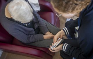 Estudante de Terapia Ocupacional da ESSALCOITÃO interage com uma pessoa idosa durante uma atividade, utilizando cartões ilustrados para promover estimulação cognitiva e comunicação.