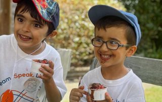 Dois meninos a comer um gelado e a sorrir bastante